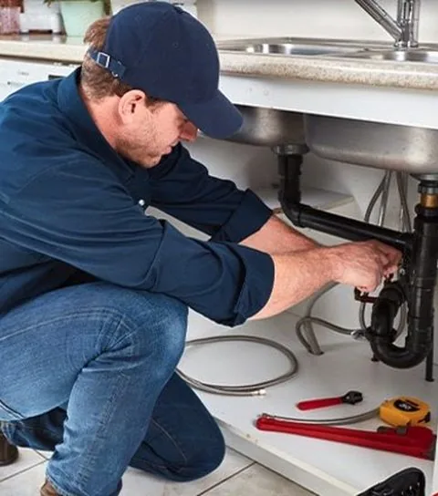 Handyman repairing plumbing under a sink