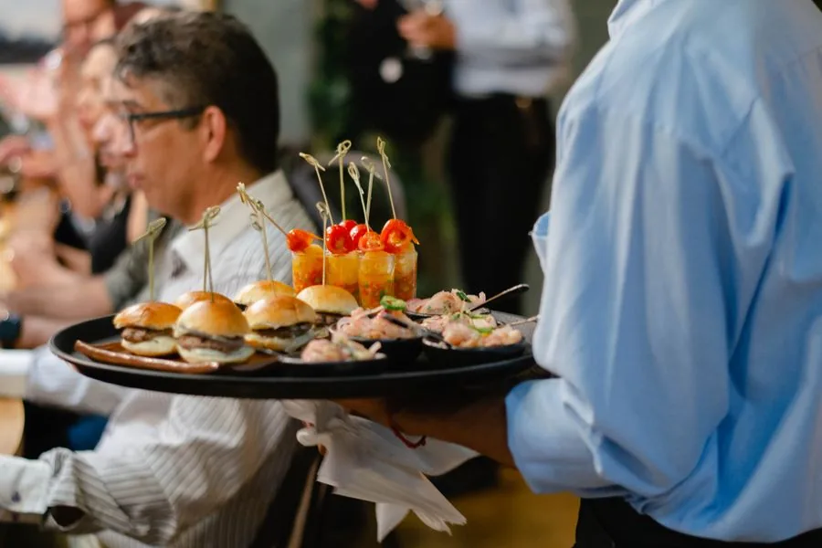 A hosting helper passing a tray of appetizers at a party