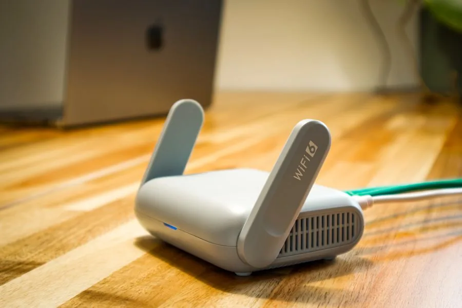 A modern Wi-Fi router set up on a wooden desk in a home