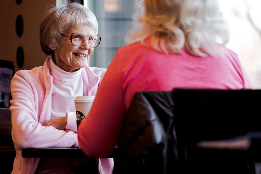 An older woman enjoying a warm conversation with her companion over coffee