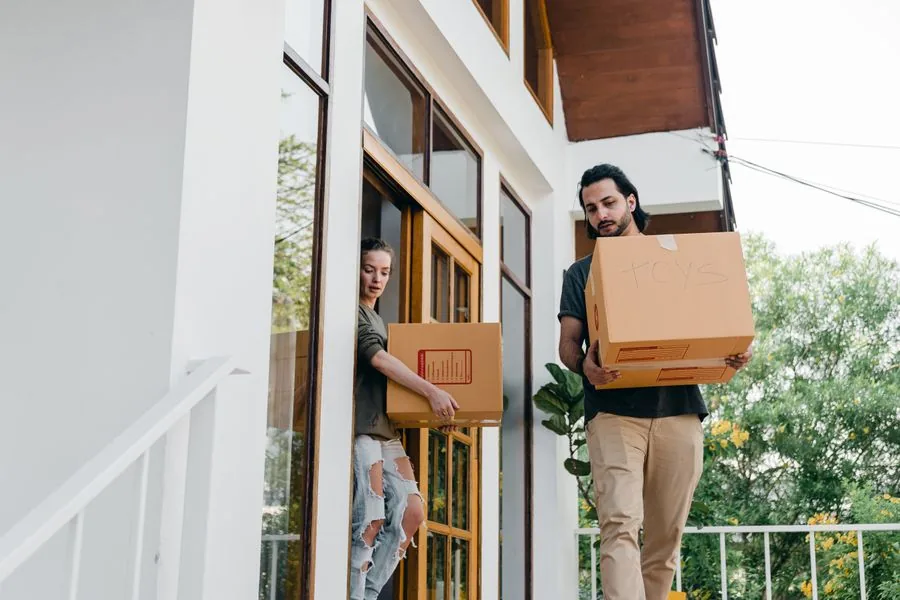 A couple carrying boxes out to load on moving day