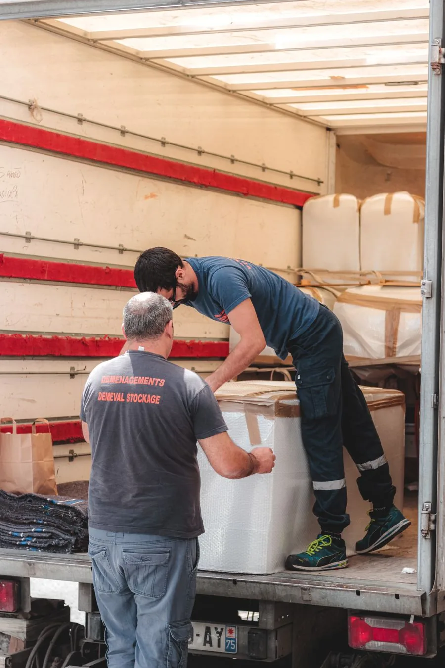 Two movers loading boxes into a rented moving truck