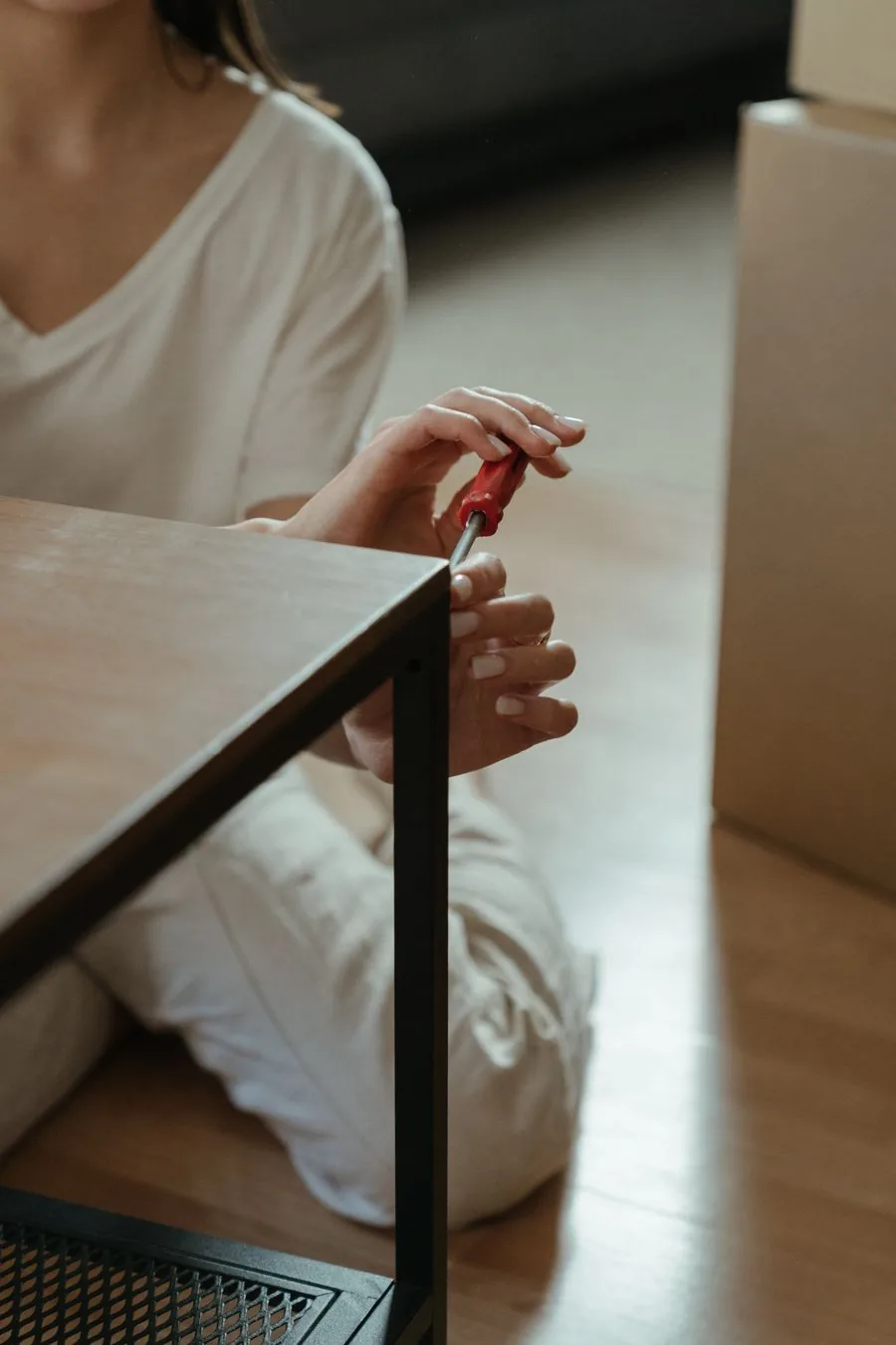 A person assembling a piece of flat-pack furniture with a screwdriver at home