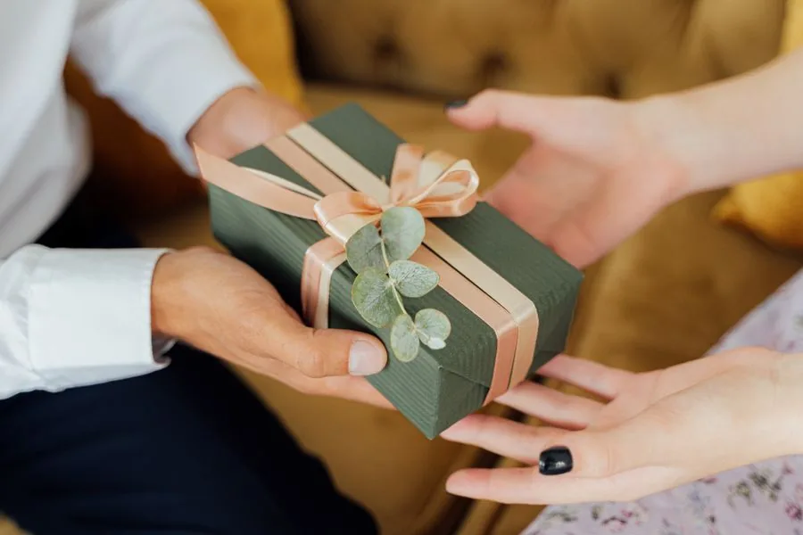 Two hands exchanging a wrapped gift box