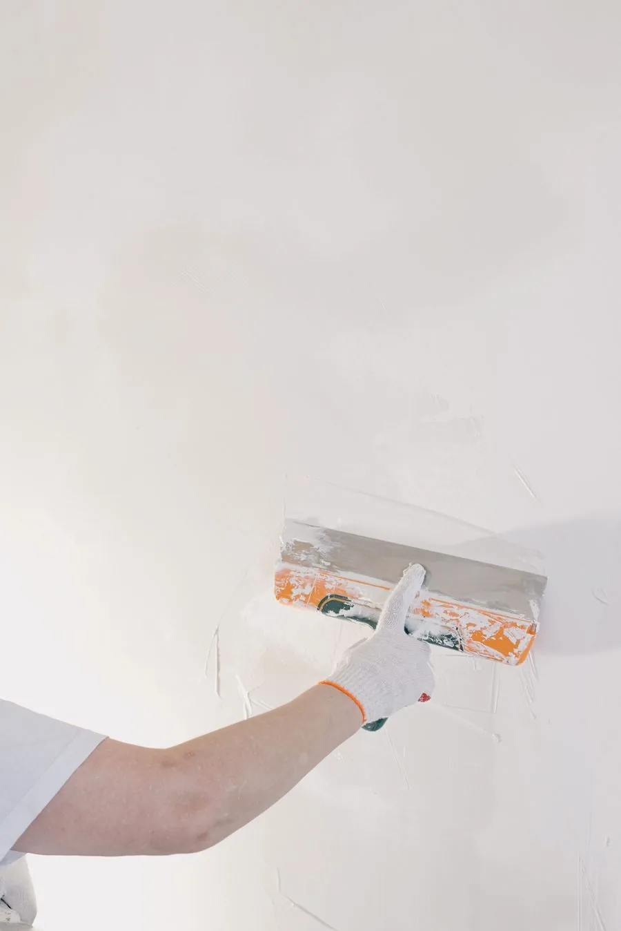 A pro smoothing a patched wall with a spatula