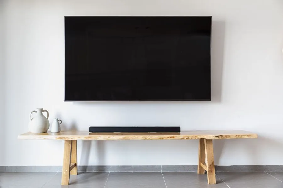 A flat-screen TV mounted level on the wall above a wooden console in a tidy living room