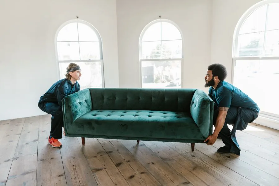 Two vetted local movers carrying a sofa inside a home