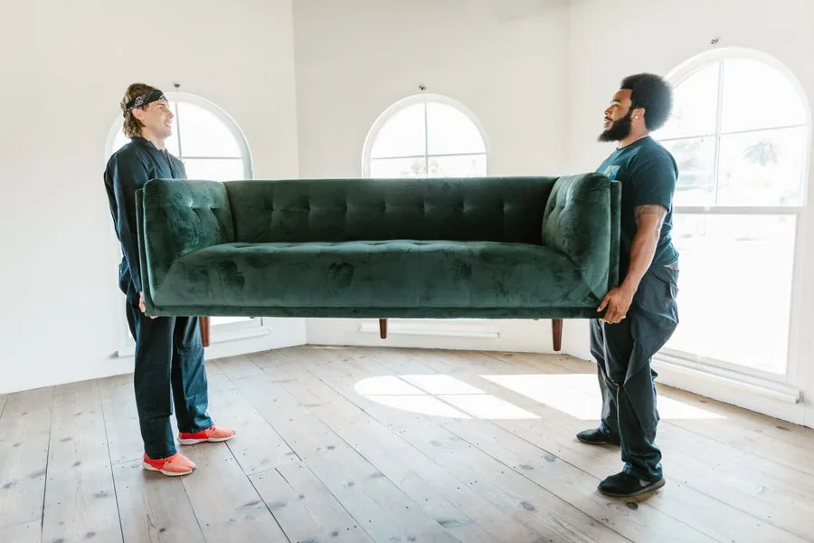 Two movers carrying a single couch out to move it