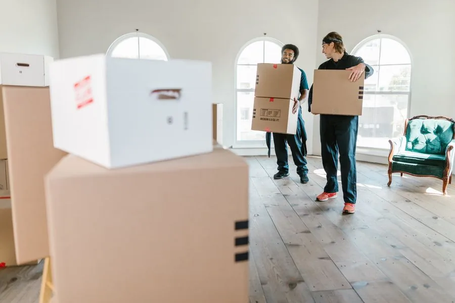 Two vetted local movers carrying boxes during a load-out