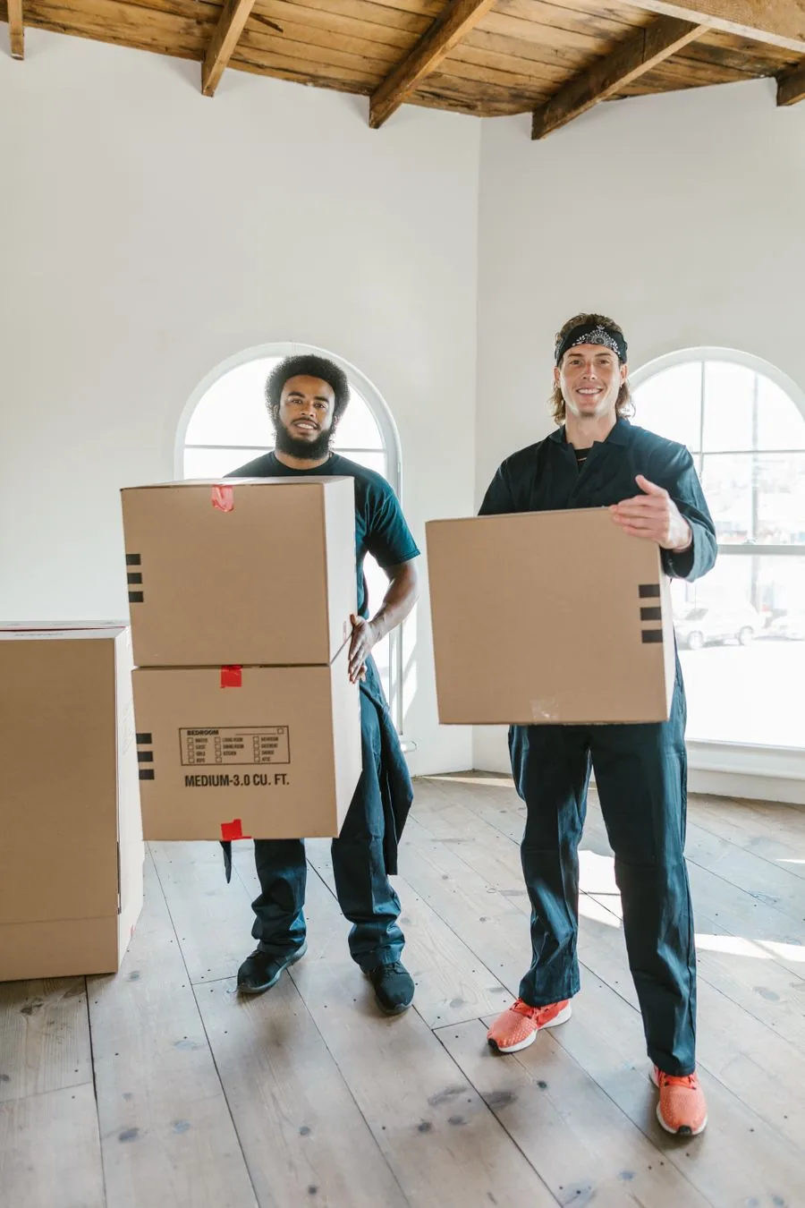 Two movers carrying cardboard boxes to load a storage unit