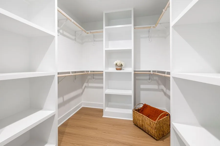 A bright, neatly organized walk-in closet with open shelves
