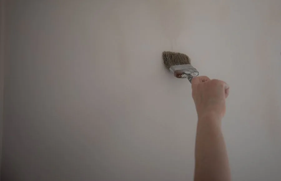 A paint brush touching up a white wall