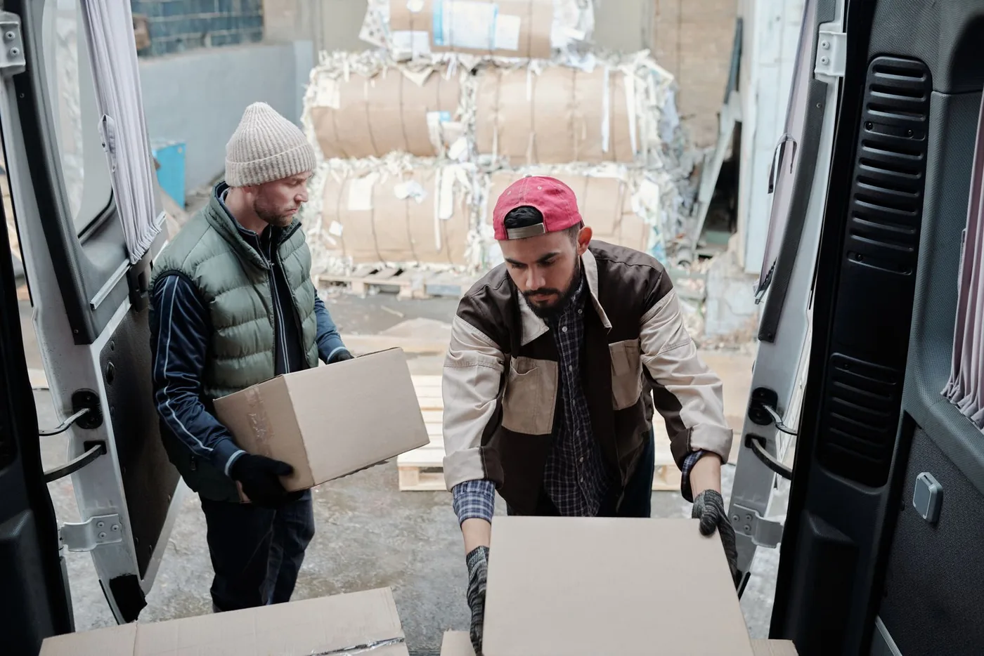 Two workers unloading boxes from a van at a dock