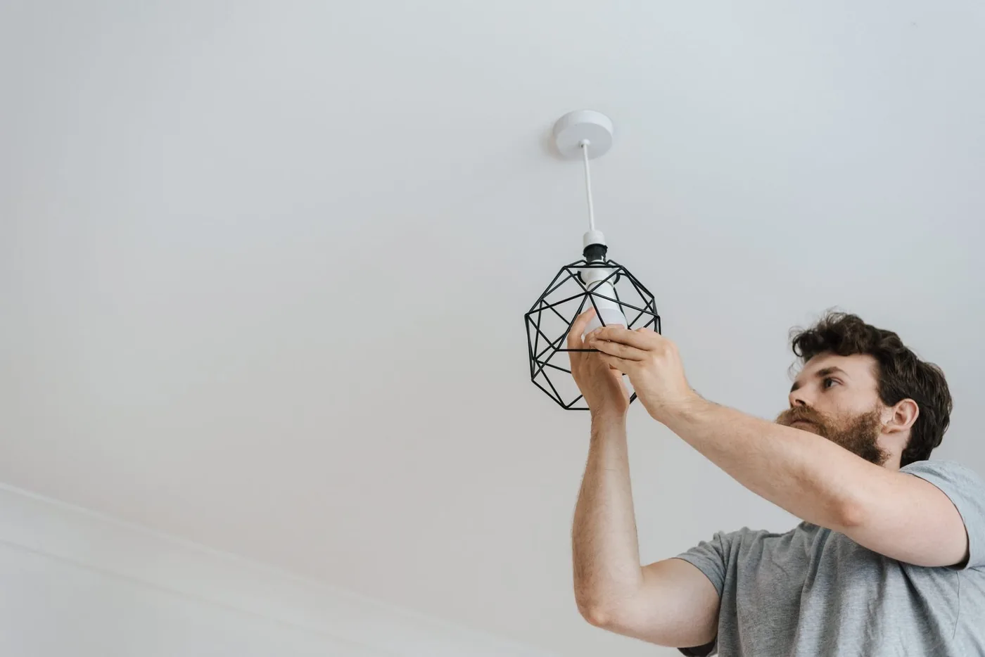 A Gopher installs a new ceiling light fixture in a neighbor's home