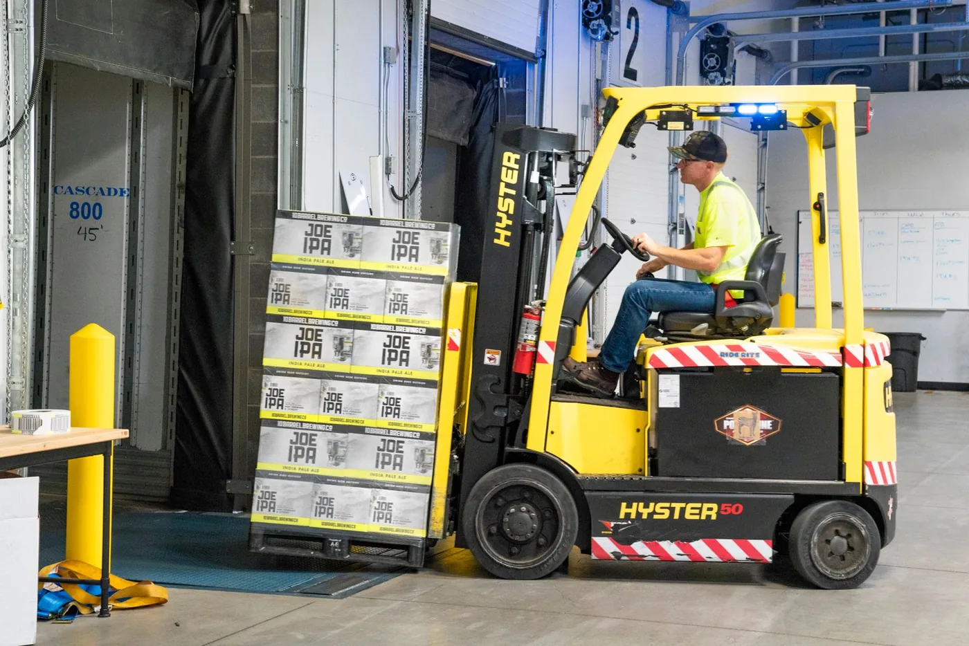 Forklift operator moving a palletized load at a dock door